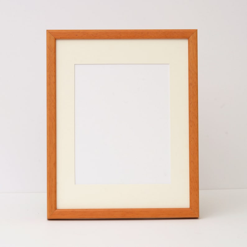 May include: A simple, wooden picture frame with a light brown finish. The frame has a white mat and is ready to display a photo or artwork.