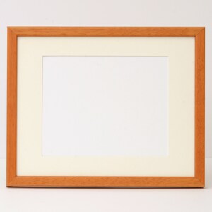 May include: A simple, wooden picture frame with a white mat. The frame is light brown and has a smooth finish.