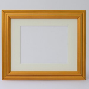 May include: A gold picture frame with a white mat. The frame has a simple, classic design.