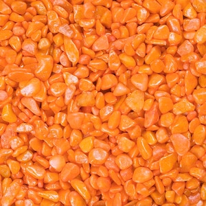 Könnte beinhalten: Ein Nahaufnahmebild einer großen Menge kleiner, orangefarbener, polierter Steine. Die Steine sind glatt und haben eine glänzende Oberfläche.