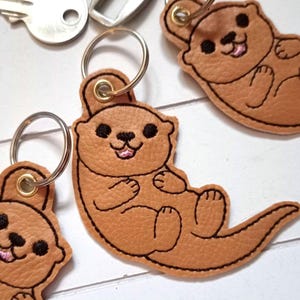 Otter Schlüsselanhänger gestickt auf hellbraunem Kunstleder, Anhänger Rucksack Taschenbaumler Geschenk