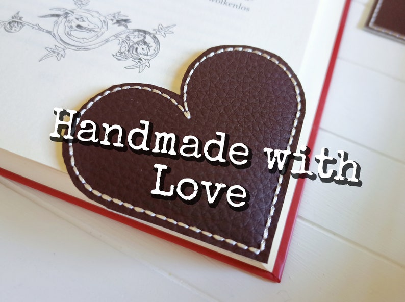 May include: A brown leather heart-shaped bookmark with white stitching and the text "Handmade with Love" in white.