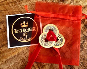 May include: Three gold-colored Chinese lucky coins with red string tied together, in a red mesh bag with a black and white tag that says "Karma by Natalie".