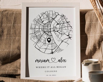 Può includere: Una stampa incorniciata in bianco che mostra una mappa stradale circolare in bianco e nero di Colonia con un segnaposto. Sotto la mappa, il testo recita: miriam ♡ alex, WHERE IT ALL BEGAN, COLOGNE e 10.10.2021. Il design è inserito in una cornice.