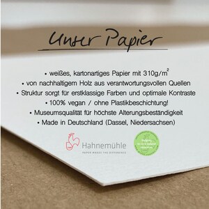 May include: Close-up of white textured paper with the text "Unser Papier" in cursive. The paper has a weight of 310g/m&sup2; and is made from sustainable wood. The Hahnem&uuml;hle logo is visible, along with text about the paper's features.