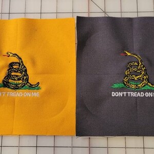 Puede incluir: Dos parches de tela con una imagen bordada de una serpiente enroscada con las palabras "Don't Tread On Me". El parche de la izquierda es amarillo y el parche de la derecha es gris.