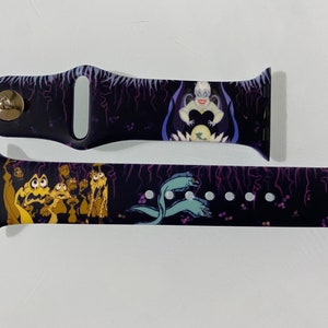 May include: A black and purple Apple Watch band with a graphic of Ursula from The Little Mermaid. The band has a dark background with purple lightning bolts and a scene of Ursula with her eels.