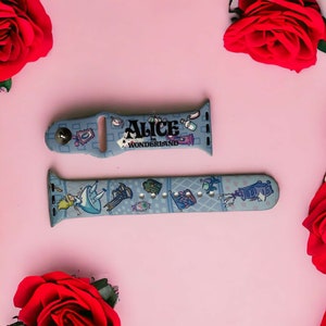 May include: A blue and white Apple Watch band with a graphic print of Alice in Wonderland characters and the text "Alice in Wonderland".