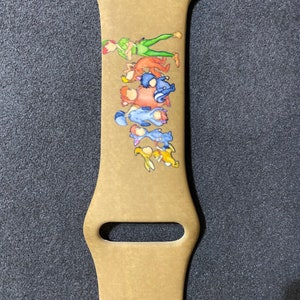 Puede incluir: Correa de reloj Apple Watch de color beige con una colorida ilustraci&oacute;n de Peter Pan y otros personajes. La correa tiene un cierre de acero inoxidable y tres orificios de ajuste. El dise&ntilde;o incluye personajes en verde, naranja, azul y amarillo.