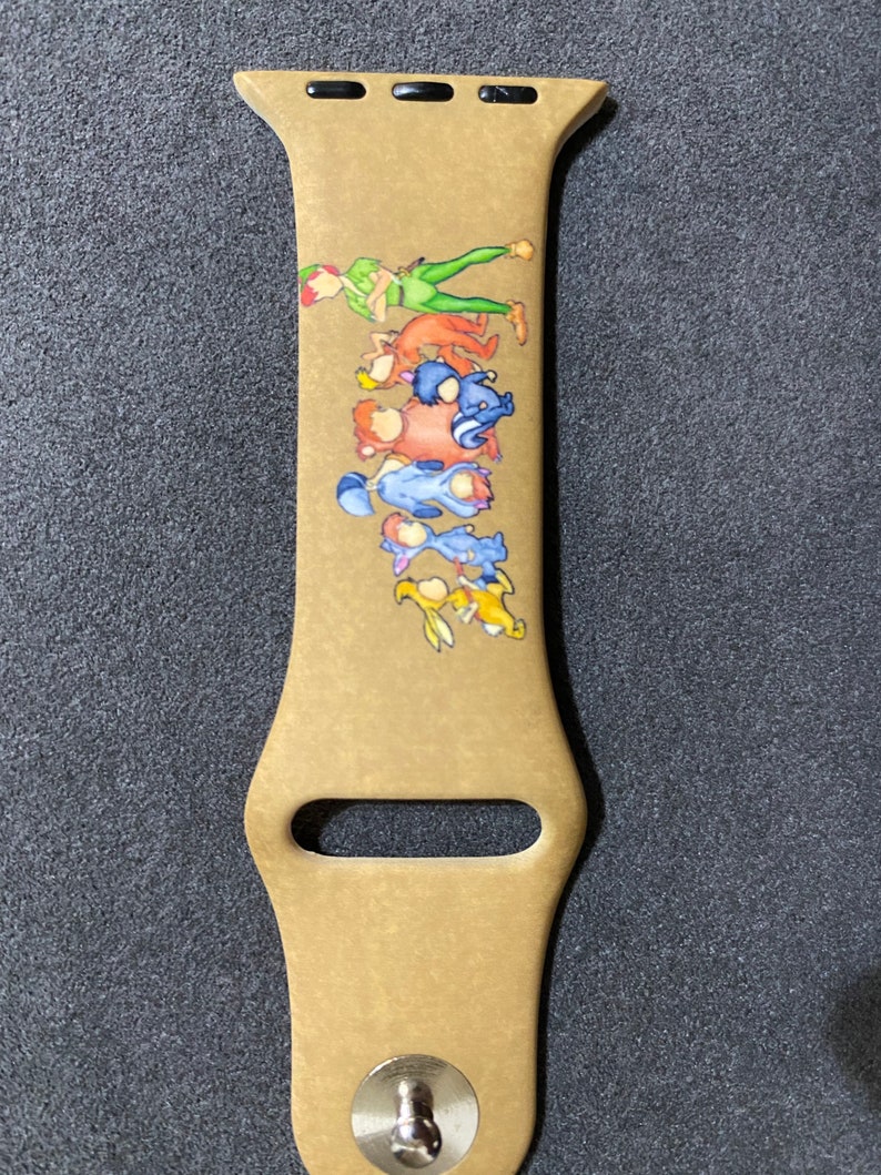 Puede incluir: Correa de reloj Apple Watch de color beige con una colorida ilustraci&oacute;n de Peter Pan y otros personajes. La correa tiene un cierre de acero inoxidable y tres orificios de ajuste. El dise&ntilde;o incluye personajes en verde, naranja, azul y amarillo.