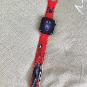 Puede incluir: Una banda roja para Apple Watch con un diseño de Spiderman. La esfera del reloj muestra la hora 9:31 y un gráfico de unicornio.