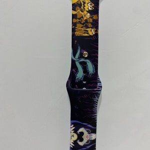 May include: A black and purple Apple Watch band with a graphic print of characters from the Disney movie The Little Mermaid. The band features Ursula, the sea witch, and the sea creatures from the movie.