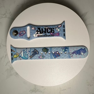 May include: A blue and white Apple Watch band with a design featuring Alice in Wonderland characters and the text "Alice in Wonderland".