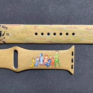 Puede incluir: Correa de Apple Watch de color beige con un mapa de Nunca Jam&aacute;s y las palabras "Lost Boys" y "Never Land". La correa tambi&eacute;n incluye ilustraciones de Peter Pan y los Ni&ntilde;os Perdidos.