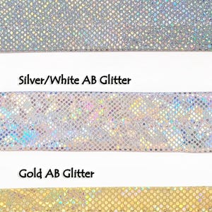 May include: Five samples of AB glitter fabric in different colors: silver/black, silver/silver, silver/white, gold, and black. The glitter is iridescent and has a subtle rainbow effect.