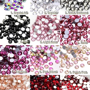 K&ouml;nnte beinhalten: Eine Sammlung von zw&ouml;lf Gruppen runder, facettierter Strasssteine mit flacher R&uuml;ckseite in verschiedenen Farben, beschriftet von 1 bis 12: Crystal AB, Crystal, Black Diamond, Jet, Light Rose, Rose, Fuchsia, Pink Vitrail, Peach Pink, Light Peach, Garnet und Siam.
