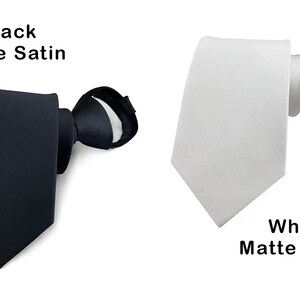 K&ouml;nnte beinhalten: Zwei Krawatten, eine aus schwarzem mattem Satin und eine aus wei&szlig;em mattem Satin. Jede Krawatte hat ein spitzes Ende und eine geknotete Halsschlaufe. Der Text "Black Matte Satin" steht &uuml;ber der schwarzen Krawatte, "White Matte Satin" darunter.
