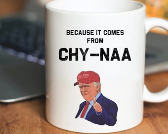 Könnte beinhalten: Eine weiße Keramik-Kaffeetasse mit einem Schwarzweißbild eines Mannes, der einen roten "Make America Great Again"-Hut trägt. Auf der Tasse steht der Text "Because it comes from Chy-naa".