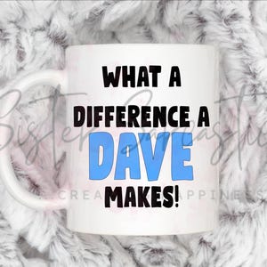 Könnte beinhalten: Weiße Keramik-Tasse mit dem Text "WHAT A DIFFERENCE A DAVE MAKES!" in schwarzer und blauer Schrift. Die Tasse hat einen weißen Henkel und steht vor einem flauschigen, weißen Hintergrund.