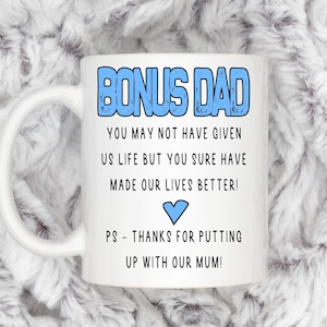 May include: White ceramic mug with a blue and white design. The mug reads "Bonus Dad" and includes the text "You may not have given us life but you sure have made our lives better!" and "PS - Thanks for putting up with our mum!"