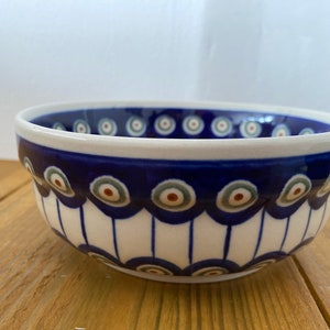 May include: A white ceramic bowl with a blue and white pattern. The bowl has a scalloped edge and a blue rim. The pattern features a series of circles with a white centre and a blue ring around the outside.