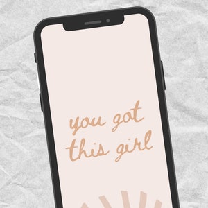 May include: A phone screen with a pink background and the text "you got this girl" in brown script. A stylized orange sun with white rays is at the bottom of the screen.