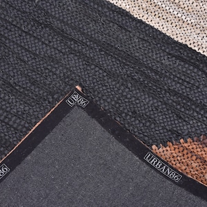 May include: Close-up of the back of a black, brown, and white leather rug with the text "URBAN86" printed on the edge.
