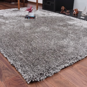 K&ouml;nnte beinhalten: Ein flauschiger, grauer Shaggy-Teppich mit weicher, flauschiger Textur. Der Teppich liegt auf einem Holzboden.