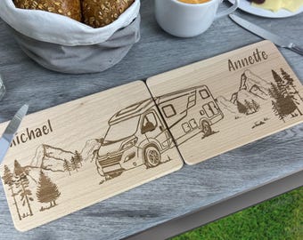 Könnte beinhalten: Zwei rechteckige Schneidebretter aus hellem Holz, die nebeneinander liegen und mit lasergravierten Abbildungen eines Wohnmobils, Bergen und Tannen versehen sind. Das linke Brett ist mit dem Namen Michael und das rechte mit Annette graviert.