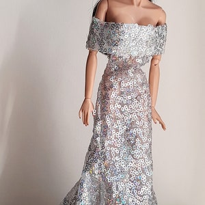 May include: A silver sequined off-the-shoulder gown with a fitted bodice and a flowing skirt.