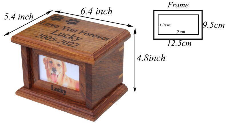 K&ouml;nnte beinhalten: Eine h&ouml;lzerne Tierurne mit einem Bilderrahmen, graviert mit dem Text "Love You Forever Lucky 2005-2022". Die Urne ist 16,3 cm lang, 13,7 cm breit und 12,2 cm hoch.