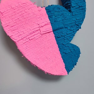 May include: A pink and blue heart-shaped pinata with a string attached to the top.