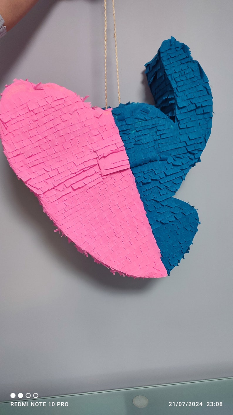 May include: A pink and blue heart-shaped pinata with a string attached to the top.