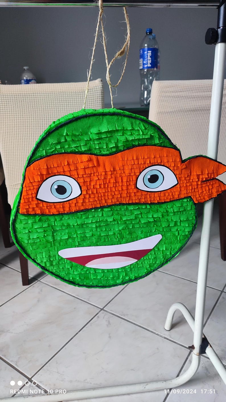 May include: Green and orange Teenage Mutant Ninja Turtles pi&ntilde;ata with a smiling face and a black eye mask.