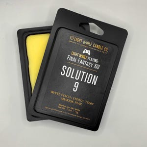 May include: Black wax melt packaging with the text "LIGHT WHILE PLAYING: FINAL FANTASY XIV SOLUTION 9". The packaging includes a yellow wax melt. The scent is "WHITE PEACH • ENERGY TONIC • MAMOOK PEAR".