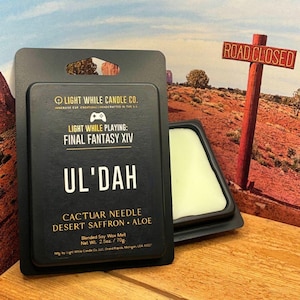 May include: A black wax melt package with the text "LIGHT WHILE PLAYING: FINAL FANTASY XIV" and "UL'DAH". The package includes a wax melt with the scent "CACTUAR NEEDLE DESERT SAFFRON • ALOE". The net weight is 2.5 oz / 70g.