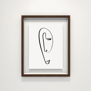 Puede incluir: Un dibujo en blanco y negro de una cara en un marco de madera marr&oacute;n.