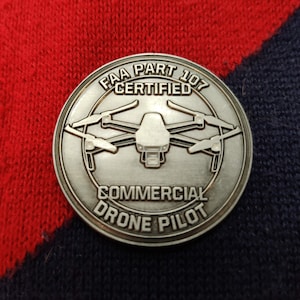 May include: A silver coin with the text "FAA Part 107 Certified Commercial Drone Pilot" and a drone graphic.