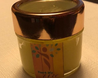 May include: A small, round jar with a gold lid and a yellow label. The label features a stylised image of a person and the text "Touch My Gift".