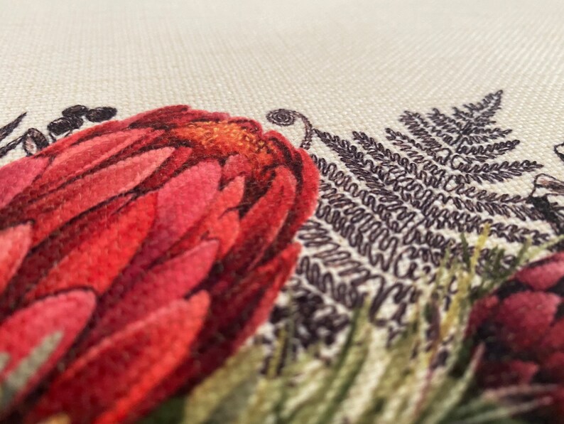 May include: Close-up of a floral fabric featuring a red flower, green leaves, and brown fern-like foliage.