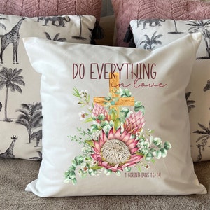 May include: White cushion with a floral design and a cross. The text "DO EVERYTHING in love" is printed on the cushion. The scripture reference "1 Corinthians 16:14" is printed below the text.