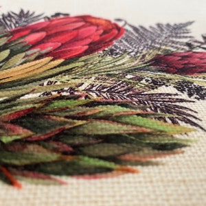 May include: Close-up of a fabric with a printed design of red and green flowers and leaves. The fabric has a textured surface.