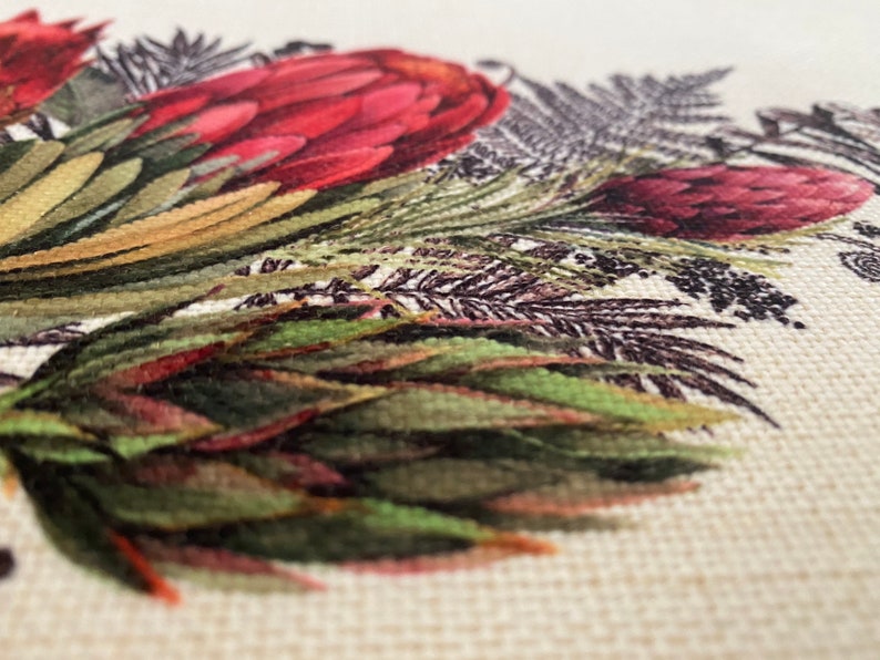 May include: Close-up of a fabric with a printed design of red and green flowers and leaves. The fabric has a textured surface.