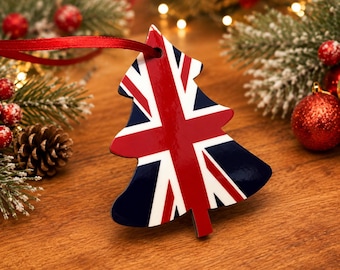May include: A Christmas tree-shaped ornament featuring the Union Jack flag in red, white, and blue. The ornament has a glossy finish and is suspended by a thin red ribbon. The design displays the iconic cross and diagonal stripes of the flag.