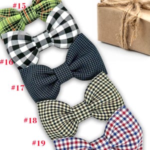 May include: A collection of bow ties in various patterns, including green plaid, black and white gingham, navy blue houndstooth, and black and cream check. Each bow tie is neatly arranged, showcasing the different designs and textures. A brown gift box tied with twine is in the background.