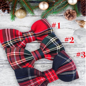 May include: Three plaid bow ties in red, green, and navy blue, each with a different pattern. The bow ties are arranged on a light wood surface, with the numbers #1, #2, and #3 next to each bow tie. Festive holiday decor is in the background.