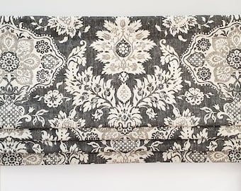 May include: A decorative window valance with a dark gray background and a repeating floral pattern in white and light gray. The valance is mounted on a dark brown metal rod with decorative finials.