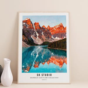 May include: A framed landscape print showing a mountain range reflected in a lake. The mountains have snow-covered peaks and are lit with orange hues. The lake is a vibrant turquoise colour. The print has the text "SK STUDIO" and "BIOPHILIC SANCTUARY COLLECTION".