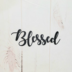 May include: Black metal wall decor with the word "Blessed" in a cursive font.