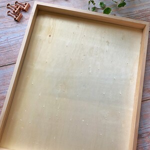 May include: A natural wood frame with a light wood-toned background. The frame is empty and ready for a picture or artwork.